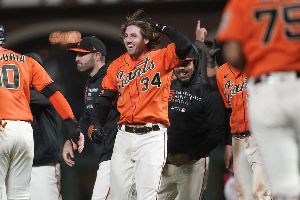 San Francisco Giants' Kevin Gausman, middle, celebrates with teammates after hitting a sacrifice fly that scored Brandon Crawford during the eleventh inning of a baseball game against the Atlanta Braves in San Francisco, Friday, Sept. 17, 2021. (AP Photo/Jeff Chiu)