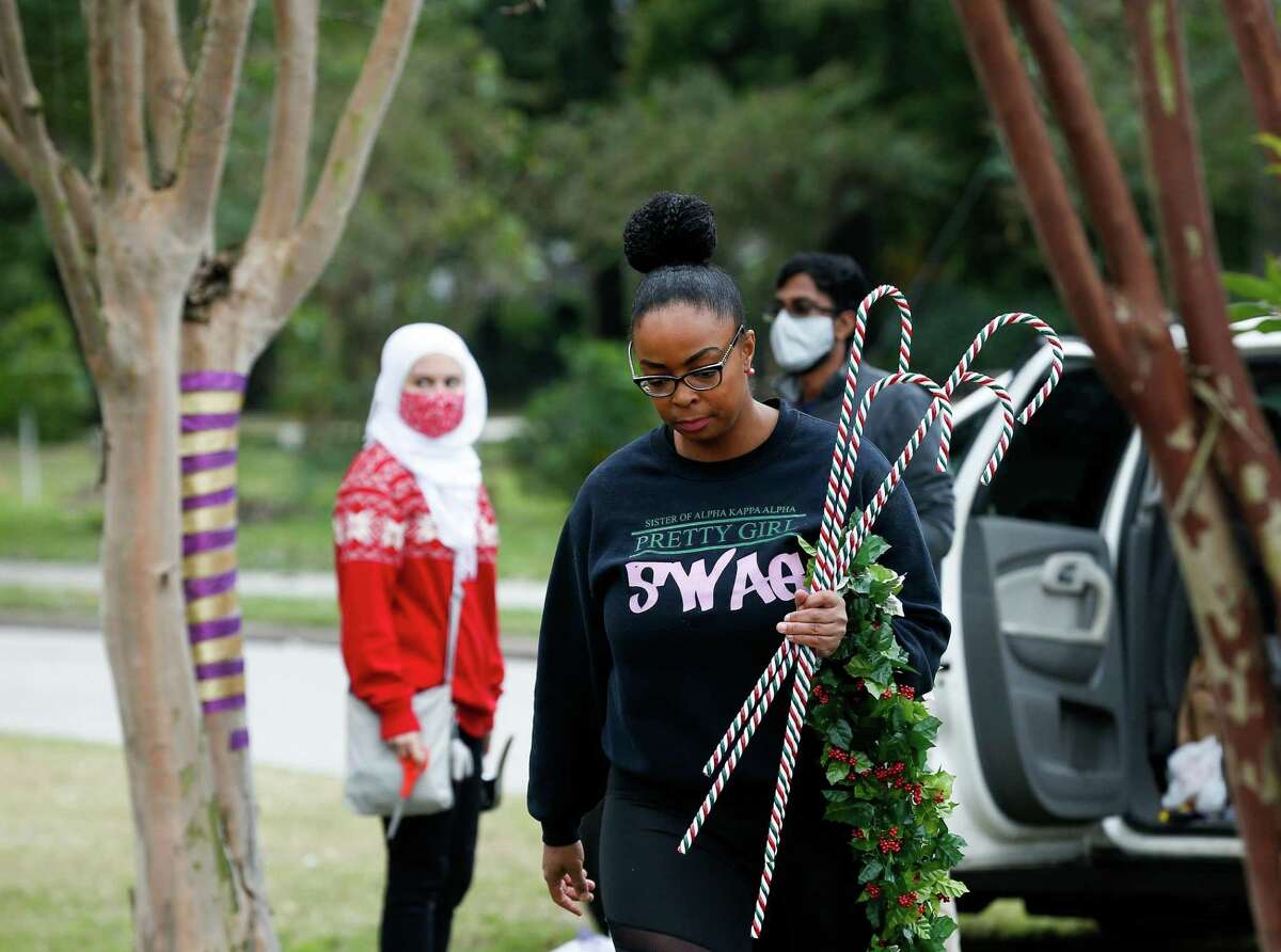 Deshara Goss, center, walks with Christmas ornaments to decorate a neighborhood esplanade on Sunday, Nov. 28, 2021, in Fifth Ward.