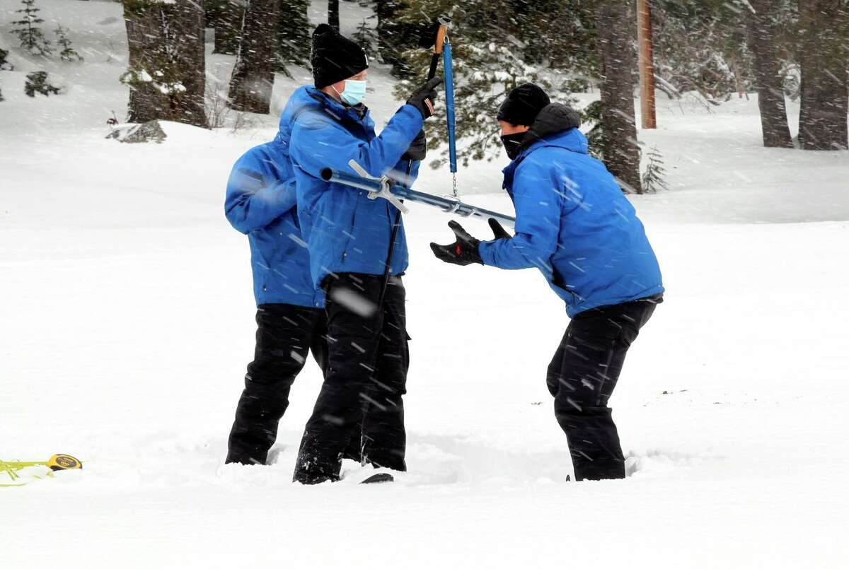 State Department of Water Resources officials Sean de Guzman, right, Florence Low, left, and Nick Ellis, center, check the weight of a snow sample as they conduct a snow survey at Phillips Station in February. The snowpack is an important source of water for California, but it could be gone within 25 years.
