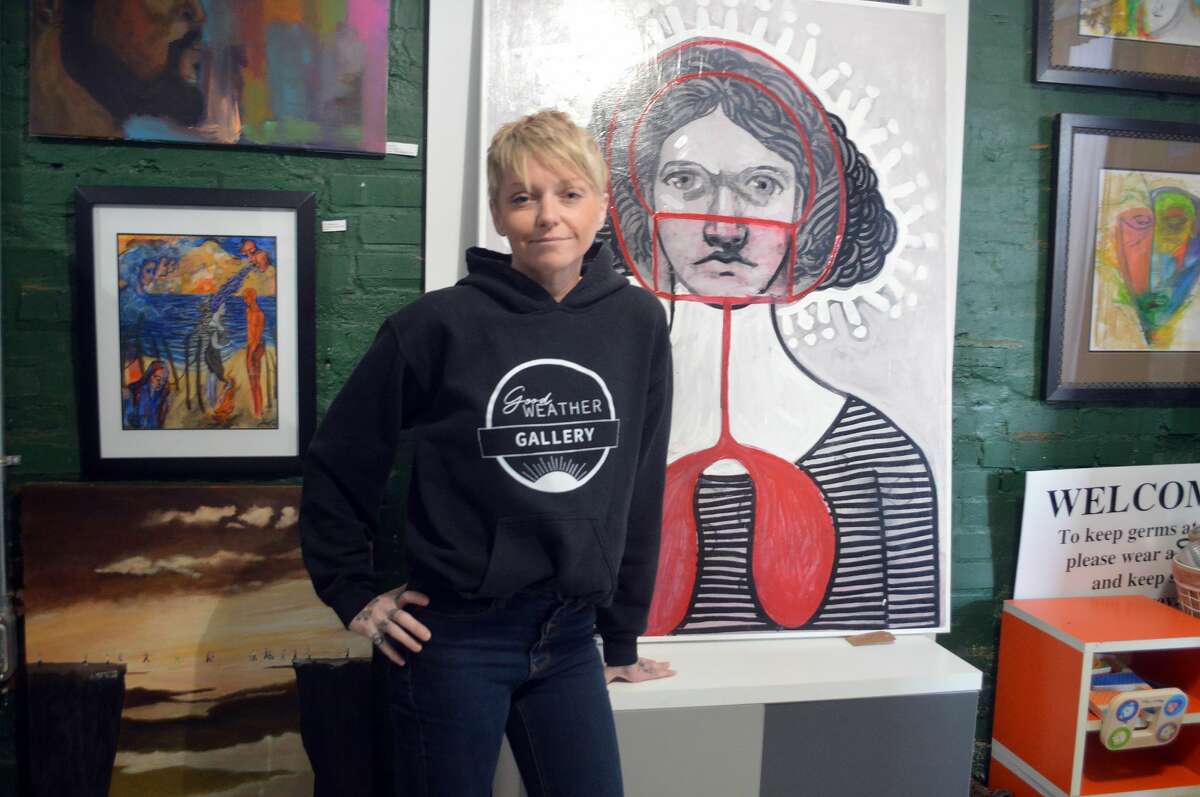 Owner Brooke Peipert is shown at Good Weather Gallery in Edwardsville, which is closing in mid-December. The artist of the painting with the mask is local artist Renee Raub-Ayers, one of a handful of artists who remained under representation since the gallery opened in September 2019.