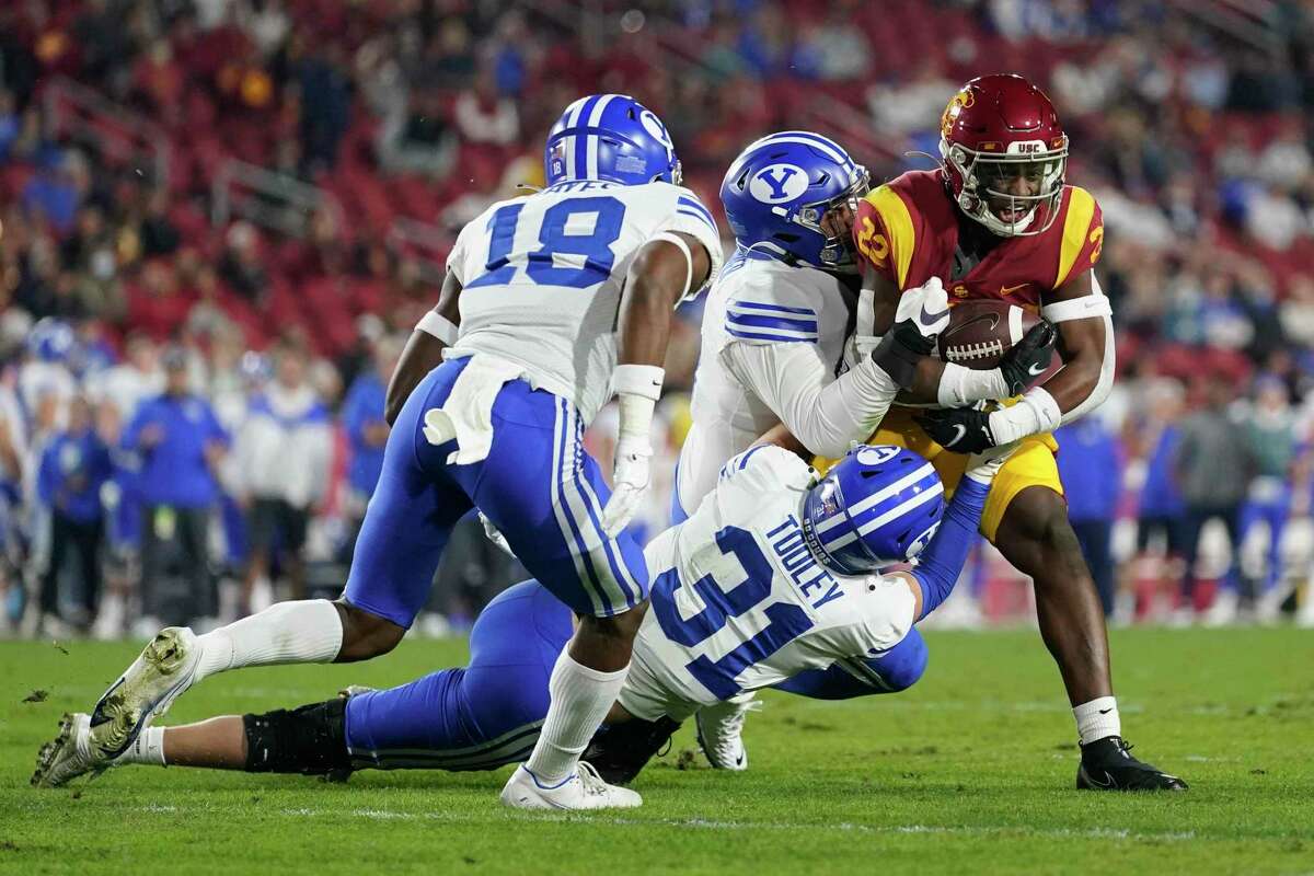 Southern California running back Darwin Barlow (22) is tackled by Brigham Young defensive lineman Alema Pilimai, center, and linebacker Max Tooley (31) during the first half of an NCAA college football game in Los Angeles, Saturday, Nov. 27, 2021. (AP Photo/Ashley Landis)