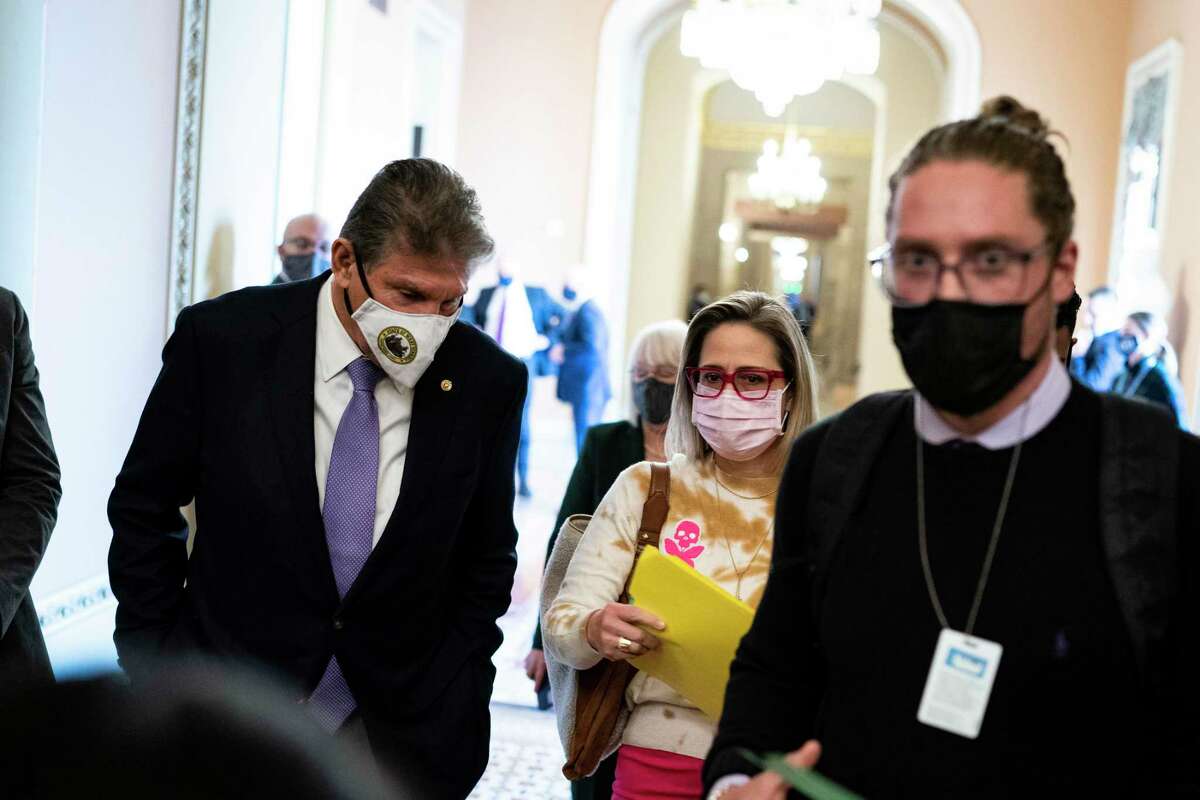 Sen. Joe Manchin (D-W.Va.), left, and Sen. Kyrsten Sinema (D-Ariz.), center, depart a Democratic policy luncheon at the Capitol in Washington on Nov. 16, 2021. They have not explicitly committed to supporting President Joe Biden’s domestic agenda that passed the House on Friday, Nov. 19, 2021. (Al Drago/The New York Times)