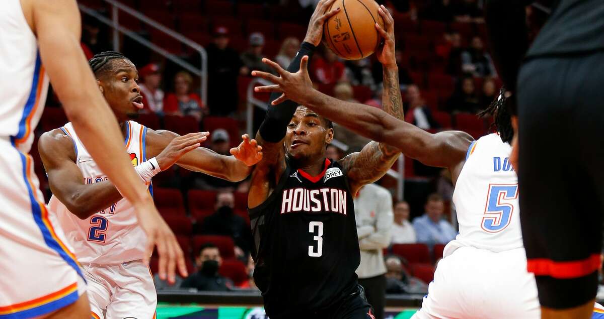 Houston Rockets guard Kevin Porter Jr. (3) dribbles past Oklahoma City Thunder guard Shai Gilgeous-Alexander (2) and forward Luguentz Dort (5) during the first quarter of an NBA game at Toyota Center on Monday, Nov. 29, 2021, in Houston.