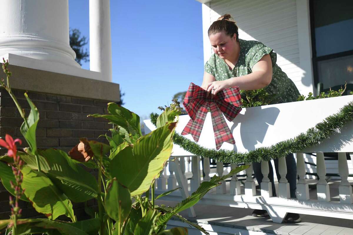Shelby Brannan puts up the porch garland and bows as she and coworkers begin decorating the Chambers House Muesum in preparation for its holiday tour December 12. The Beaumont Heritage Society will decorate the John Jay French House later this week. Photo made Monday, November 29, 2021 Kim Brent/The Enterprise