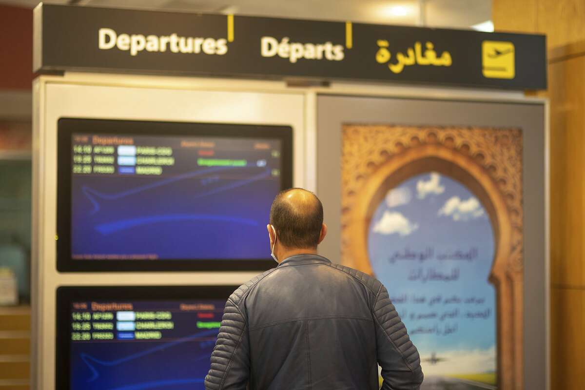 A traveler checks a screen showing cancelled and departing flights at a terminal in Rabat airport, Morocco, Monday, Nov. 29, 2021. Morocco announced it would suspend all incoming air travel from around the world starting Monday for two weeks because of the rapid spread of the new omicron variant, the government's committee in charge of monitoring COVID-19 announced Sunday. (AP Photo/Mosa'ab Elshamy)