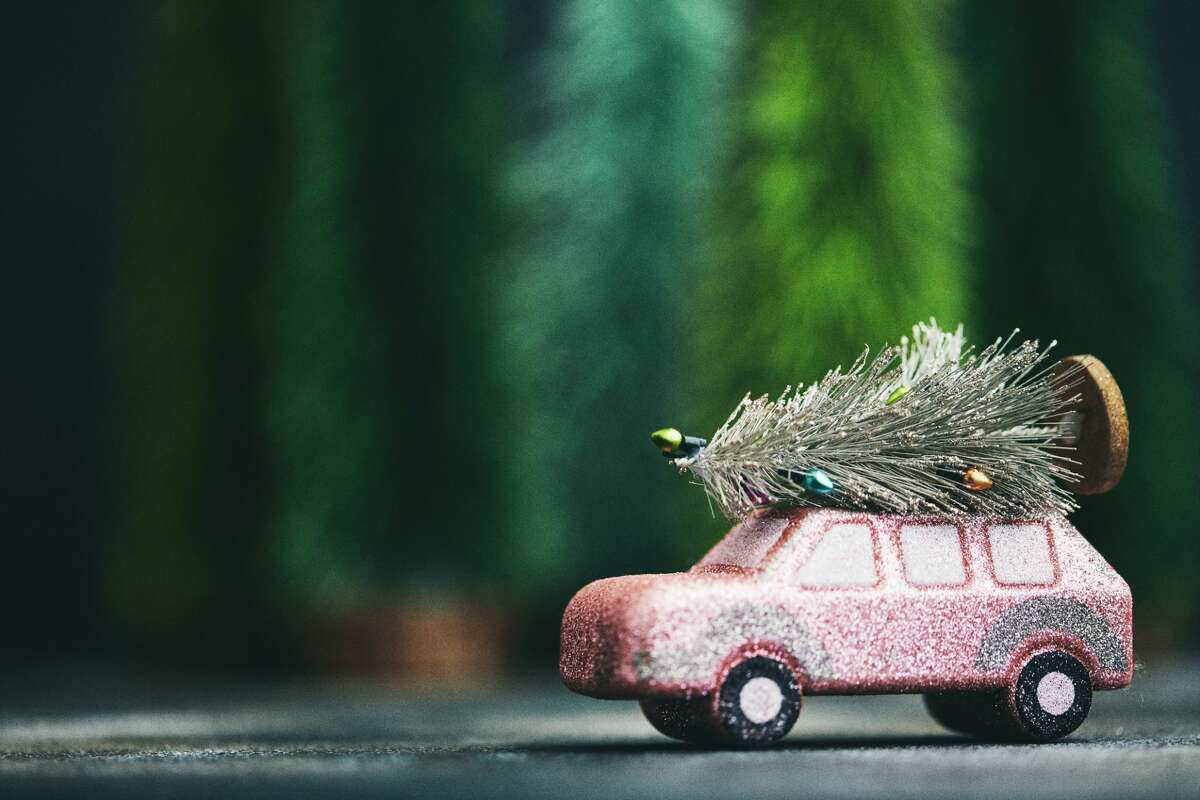 Pink car transporting Christmas tree. Christmas holiday background.