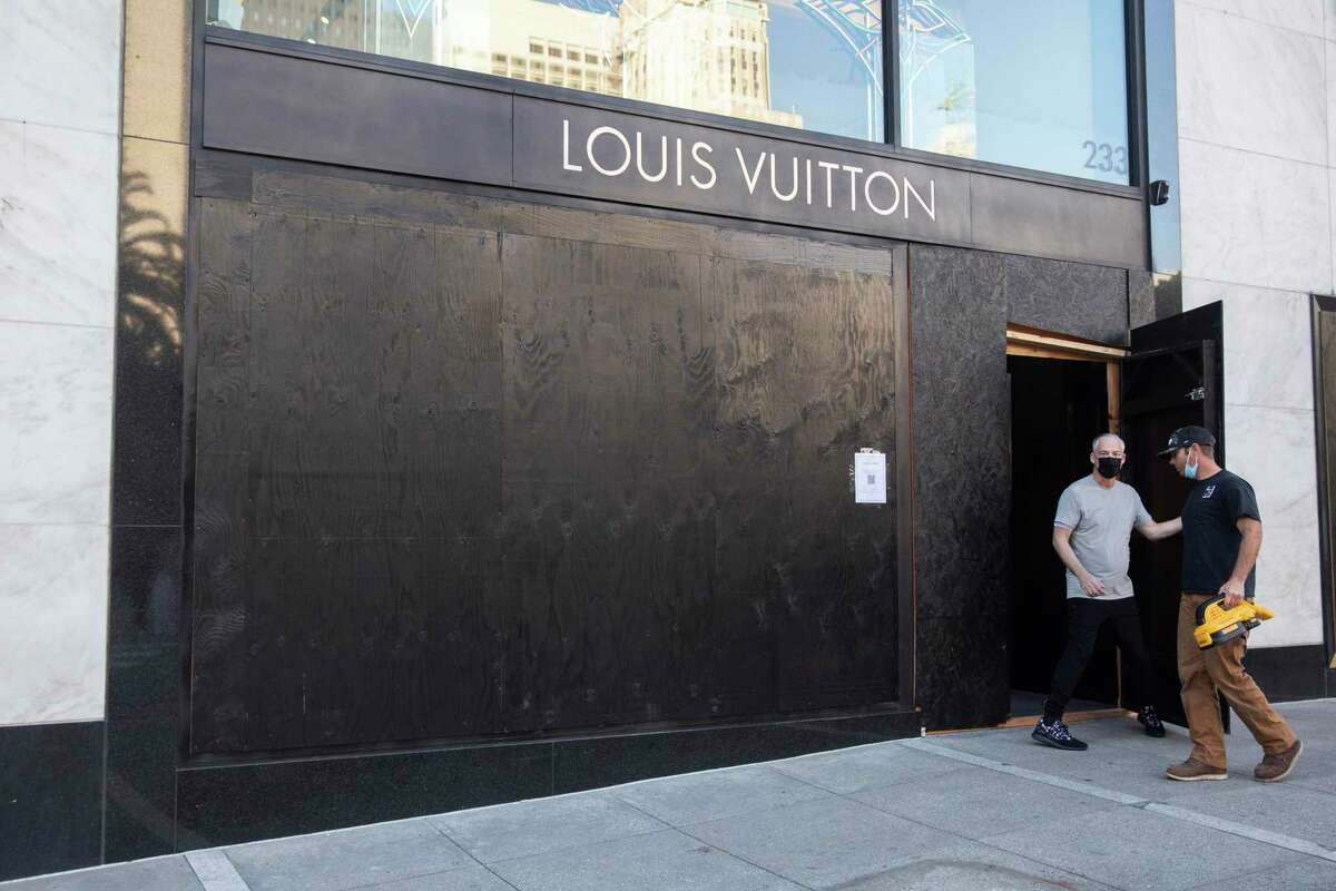 A construction worker enters a boarded up Louis Vuitton at Union Square in San Francisco, Calif. Friday, Nov. 26, 2021.