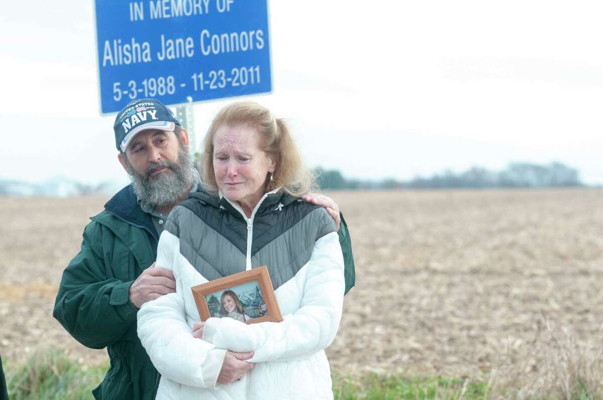 David and Laurie Connors join others Tuesday at the site where their daughter, Alisha J. Connors, died Nov. 23, 2011, in an accident involving a drunk driver. A sign was placed at the site to honor Alisha Connors, seen in the photo her mother is holding, and to remind others not to drink and drive. Greene County Sheriff Rob McMillen, members of Mothers Against Drunk Driving of Morgan County and friends attended the sign dedication and remembrance service. 