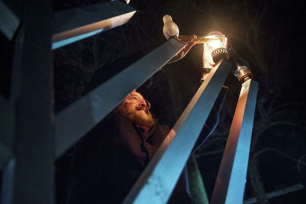 Rabbi Levi Stone of the Chabad Schneerson Center of Jewish Life lights a candle on the second night of Hanukkah, Monday, Nov. 29, 2021 on the Town Green in Wilton, Connecticut. A crowd of around 50 people attended the Menorah lighting.