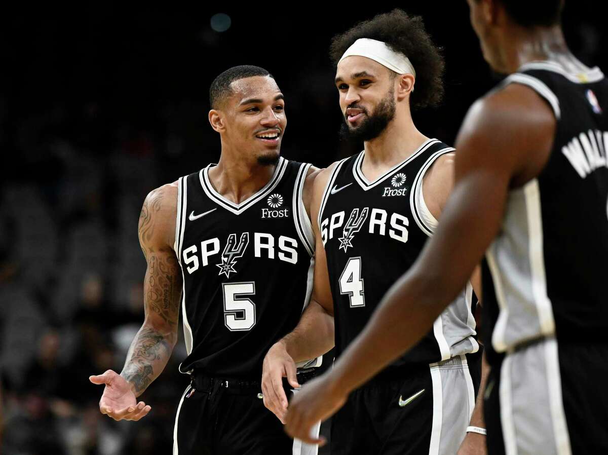 San Antonio Spurs' Dejounte Murray (5) and Derrick White talk during a time out in the second half of an NBA basketball game against the Washington Wizards, Monday, Nov. 29, 2021, in San Antonio. San Antonio won 116-99. (AP Photo/Darren Abate)