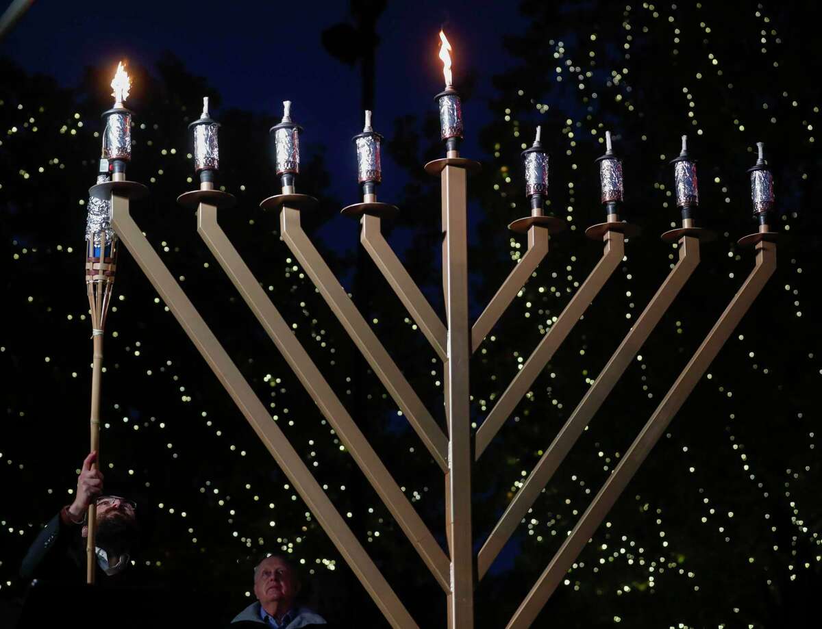 Rabbi Mendel Blecher lights a nine-foot, seven branched menorah during the annual menorah lighting to celebrate Hanukkah at Market Street, Thursday, Dec. 17, 2020, in The Woodlands. For the last decade, Chabad of The Woodlands has held the event to celebrate the Jewish holiday tradition as a community-wide celebrate, which features a nine-foot, seven-branched menorah.
