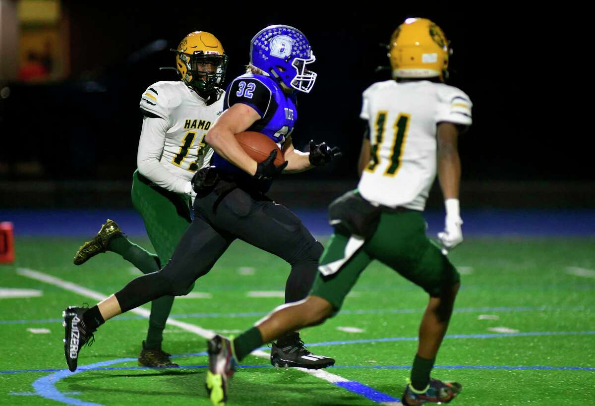 Darien’s Tighe Cummiskey (32) carries the ball on his way to a touchdown during the Class LL football playoff game against Hamden in Darien, Conn., on Tuesday, Nov. 30, 2021. Converging on Cummiskey is Hamden’s Dylan Nash (13), in back and Anthony Bolden II (11).