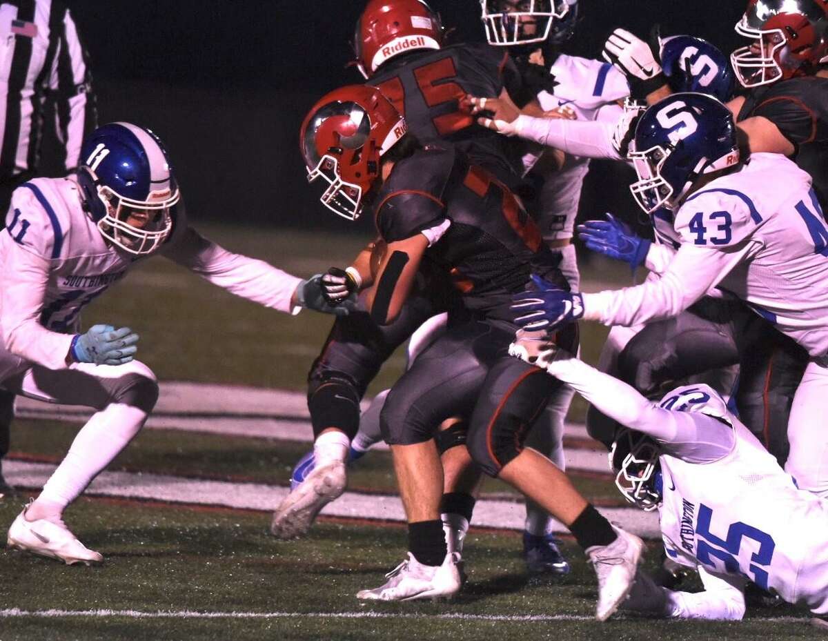 New Canaan’s Conor Bailey (20) carries while Southington’s Kameron Beaudoin (11), Jared Guida (25) and Alexander Maindon (43) close in for the tackle during a CIAC football quarterfinal on Tuesday, Nov. 30, 2021 at Dunning Field in New Canaan, Conn.