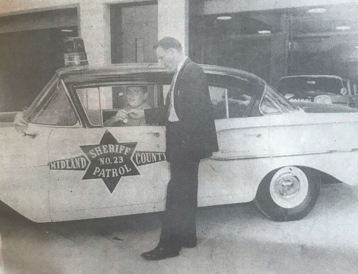 One of the first Midland County Sheriff's Department road patrol vehicles in 1958. Capt. John Smallwood hands the car keys to a deputy waiting to head out on patrol. 