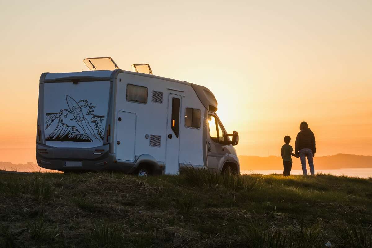 FILE— A mother and child look out on a sunset beside their RV.