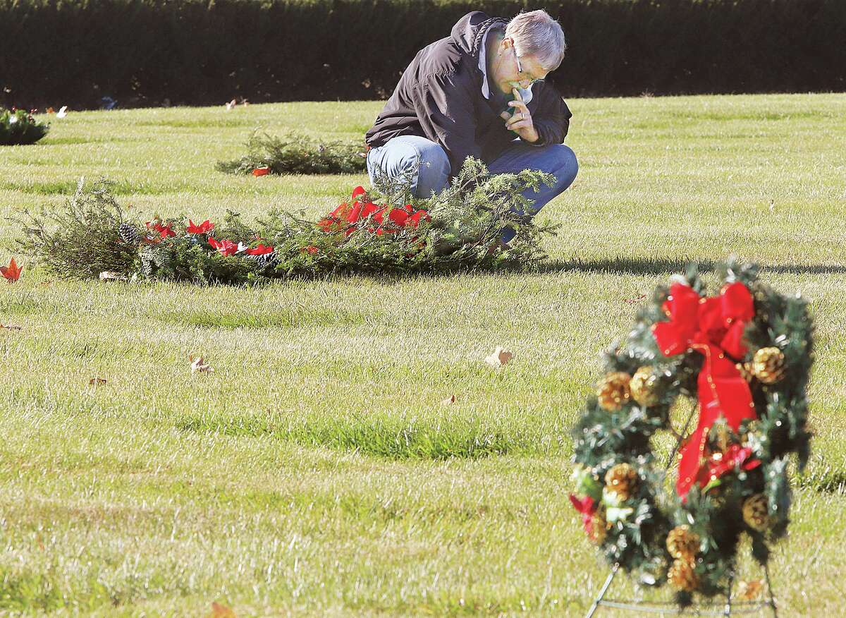John Badman|The Telegraph A man takes a moment to reflect Wednesday after placing a grave blanket in Rose Lawn Memory Gardens cemetery in Bethalto. Hundreds of graves at the cemetery have already been decorated for the season with grave blankets, traditional wreaths and Christmas tree shaped wreaths. Many people will visit and remember loved ones lost across the area this month.