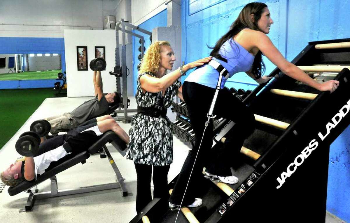 Platium Fitness owner Anna Lamorte, center, instructs her daughter Elena Lamorte, 28, of Danbury, on the Jacobs Ladder equipment, during a workout session at the center in Danbury, Tuesday, Sept. 21, 2010.