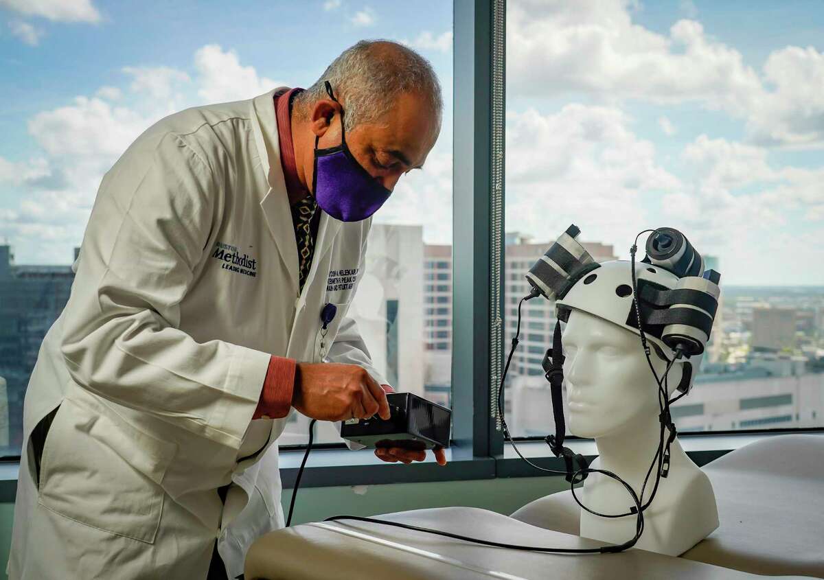 Dr. Santosh A. Helekar adjusts the experimental helmet he is developing with Dr. David Baskin that they are testing to attack cancer cells in the brain using magnets, Wednesday, Oct. 13, 2021, at Houston Methodist Hospital in the Texas Medical Center.