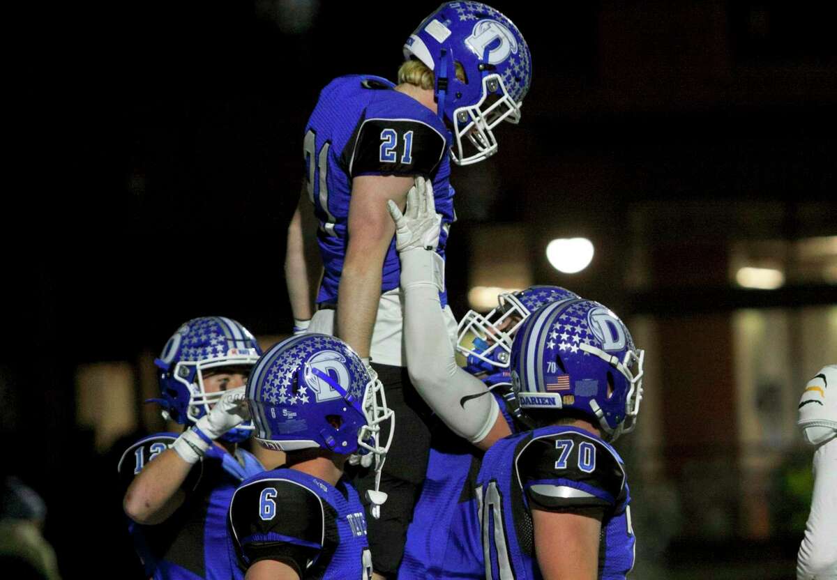 Darien’s Jeremiah Stafford (21) is hoisted into the air by teammate Karson Drake (71) after Stafford scored a touchdown during the Class LL quarterfinals on Tuesday.