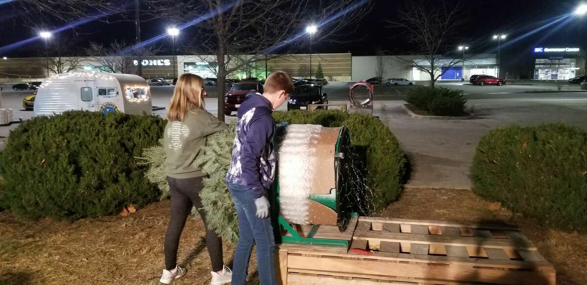 Arabella Kirbach and James Gray get ready to wrap a tree Tuesday at the Edwardsville Lions Club Tree Lot on Troy Road. 