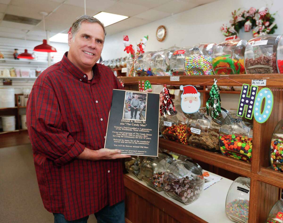 Donald Baker, Jr, holds a plaque honoring his father, Donald Baker, Sr., at The Candy House, Wednesday, Dec. 1, 2021, in The Woodlands. The new owners of The Candy House will honor his father Thursday with a dedication ceremony along with a portion of the store’s sales for the next three days to be dedicated to a non-profit set up by Baker’s granddaughter in his memory.