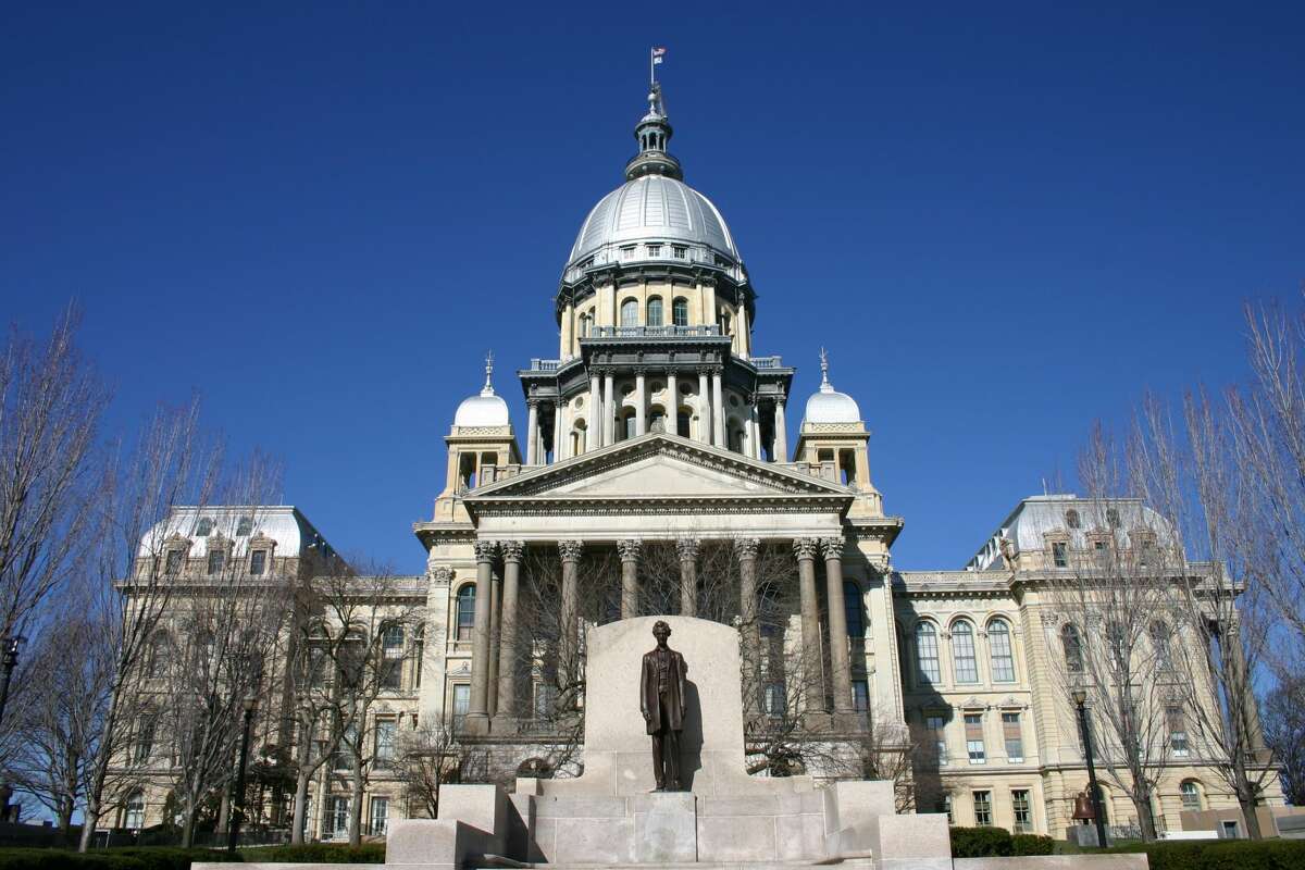 Illinois State Capitol Building with Abraham Lincoln statue and a clear blue sky.
