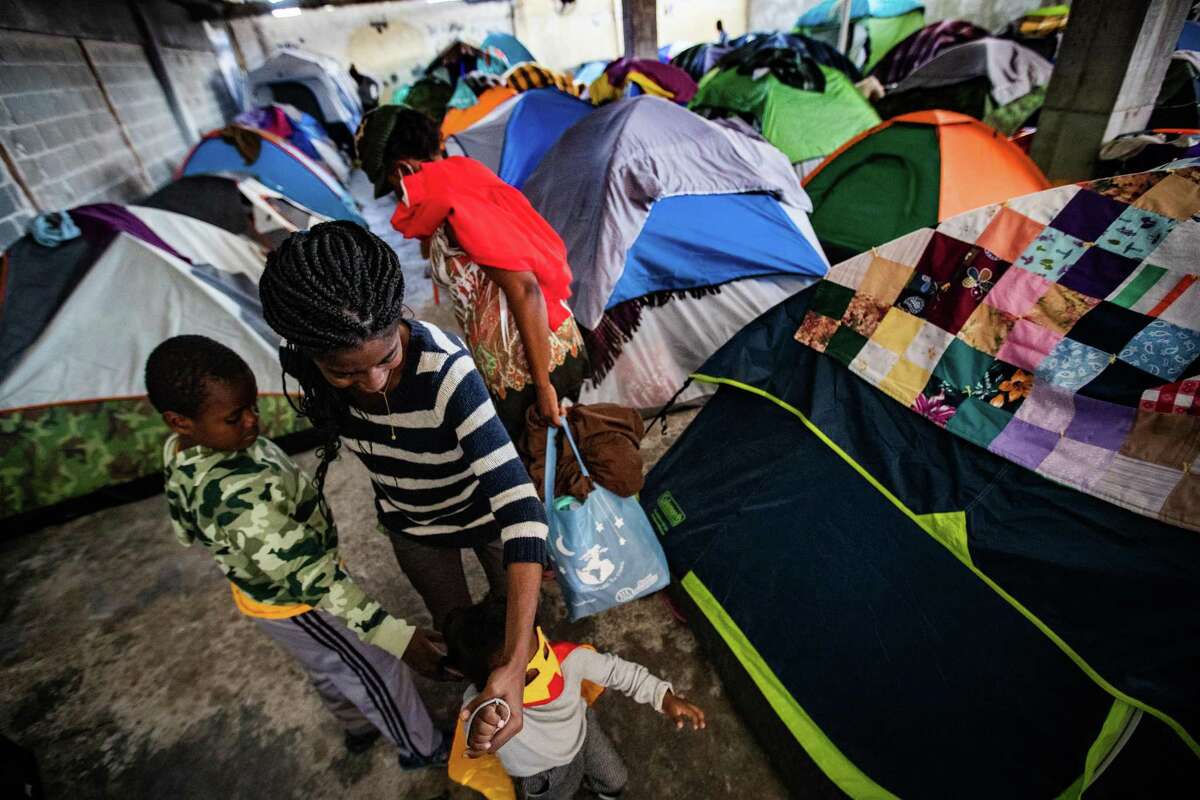 A family walks among dozens tents at the Terraza Fandango shelter, Friday, Nov. 19, 2021, in Ciudad Acuña. The shelter provided help to migrant families, mostly of Haitian origin, until they were moved to other Mexican towns.