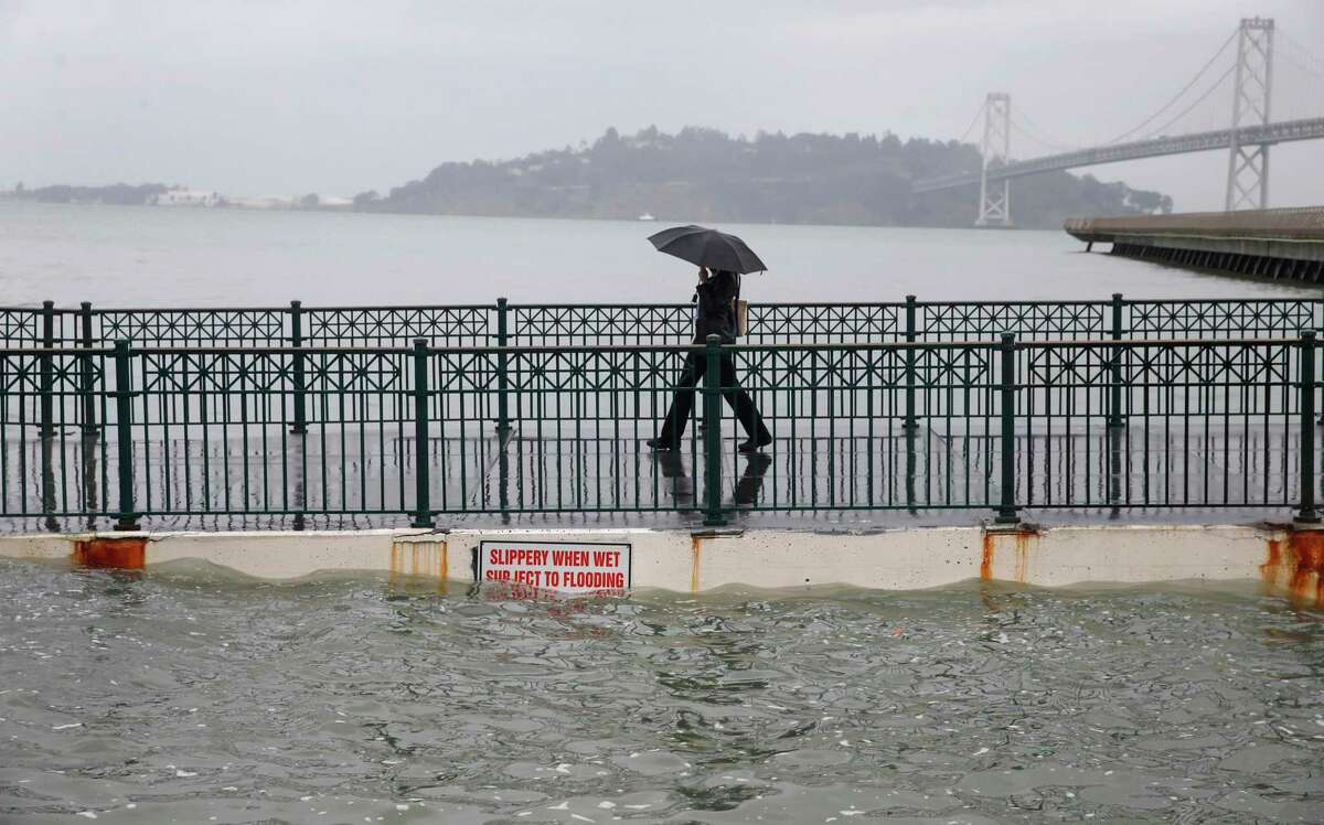 Luna Taylor walks off of Pier 14 during the peak of the high tide along the Embarcadero in San Francisco, Calif. in a 2015 photo. King tide conditions were expected to cause coastal flooding across much of the Bay Area through the weekend.