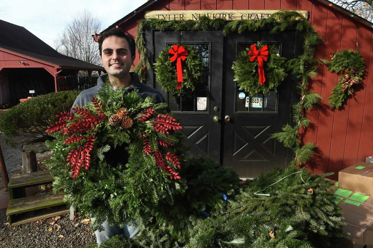 Tyler Newkirk, owner of the Tyler Newkirk Craft Co., is photographed at his store in West Haven with one of his handmade decorated wreaths Dec. 1, 2021.