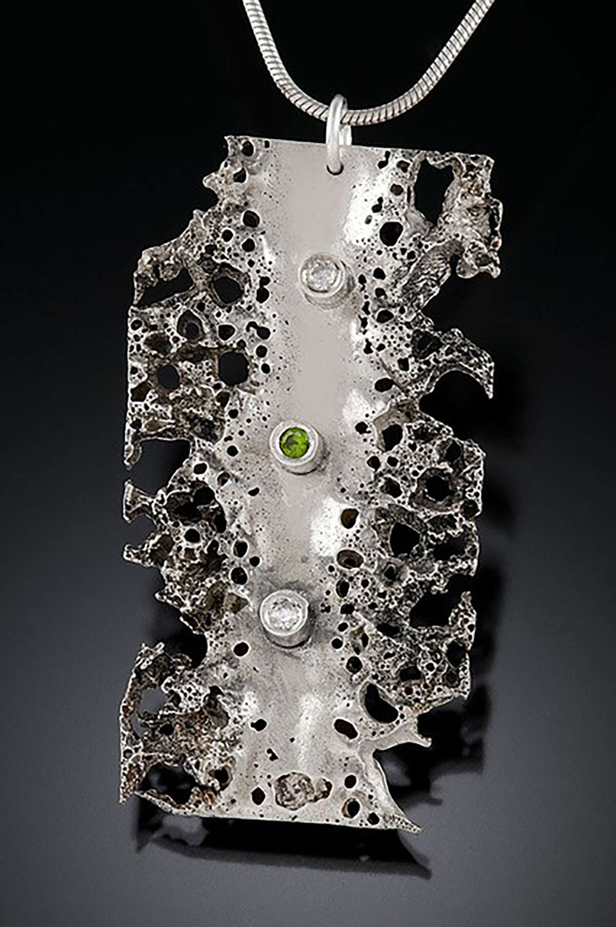 A metalsmithing technique known as perforation gives this piece of jewelry by Leigh Roberts a cratered look.