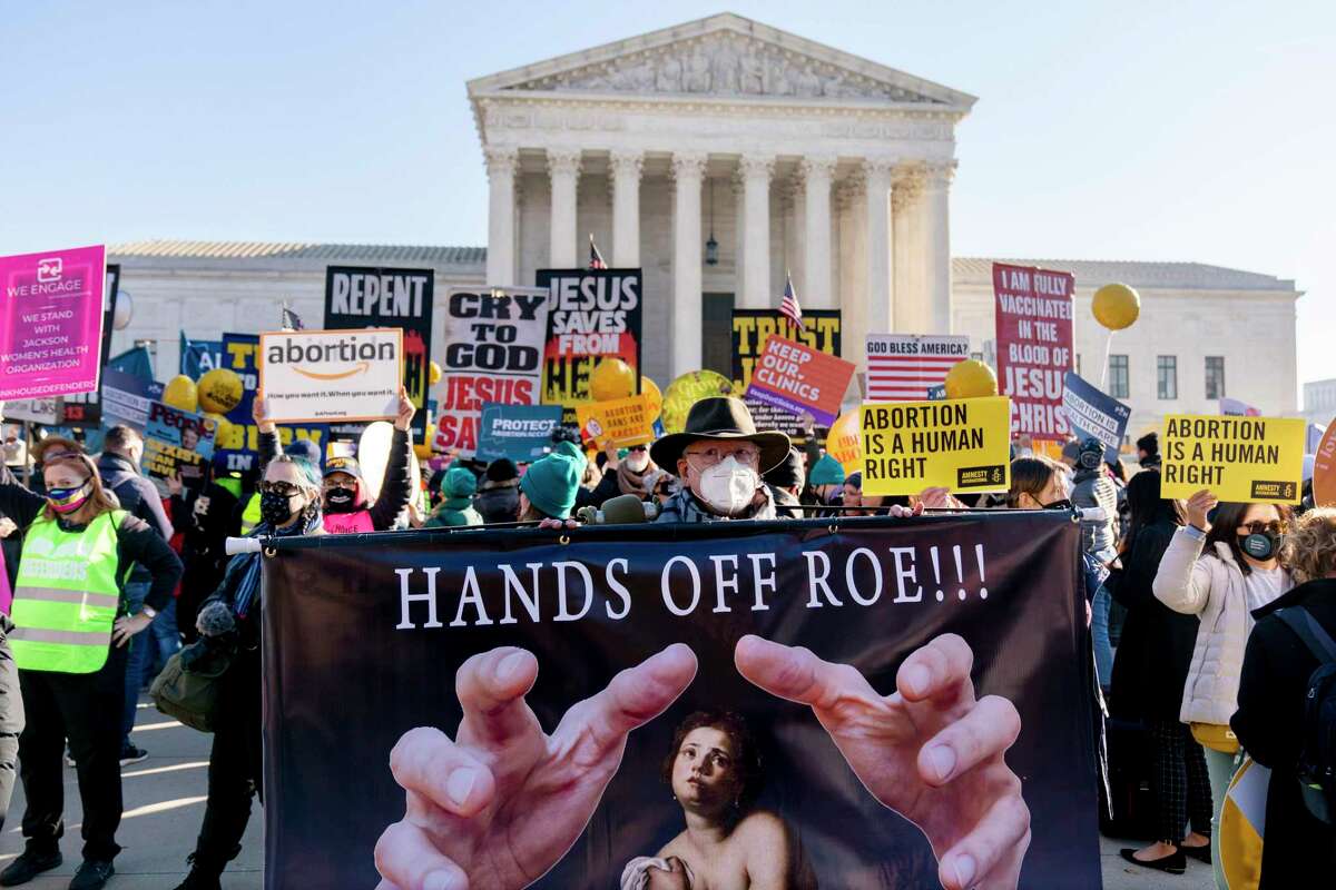 Stephen Parlato of Boulder, Colo., holds a sign that reads "Hands Off Roe!!!" as abortion rights advocates and anti-abortion protesters demonstrate in front of the U.S. Supreme Court, Wednesday, Dec. 1, 2021, in Washington, as the court hears arguments in a case from Mississippi, where a 2018 law would ban abortions after 15 weeks of pregnancy, well before viability. (AP Photo/Andrew Harnik)