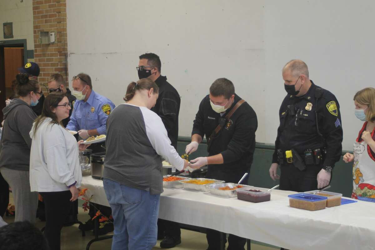 Police officers and first responders from the City of Manistee help serve food to CASMAN Academy students during the annual Thanksgiving feast on Thursday.