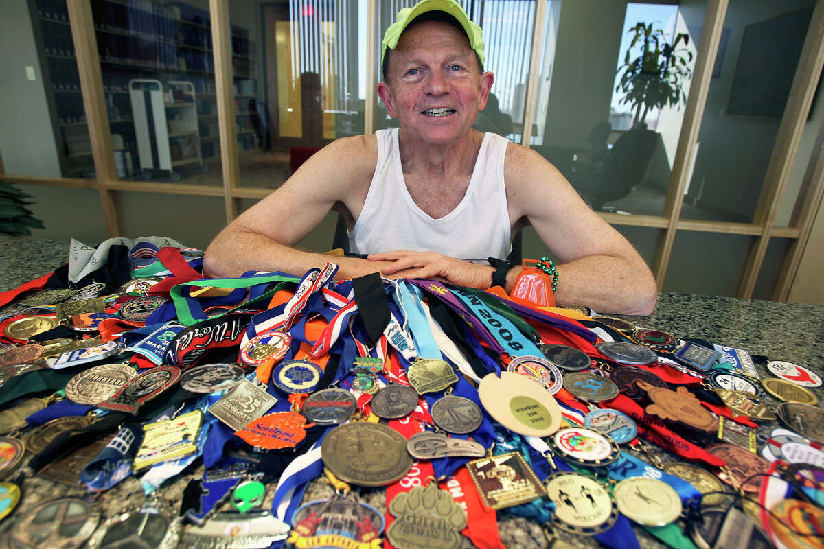Larry Macon displays his collection of 105 marathon finisher medals accumulated in a single year.