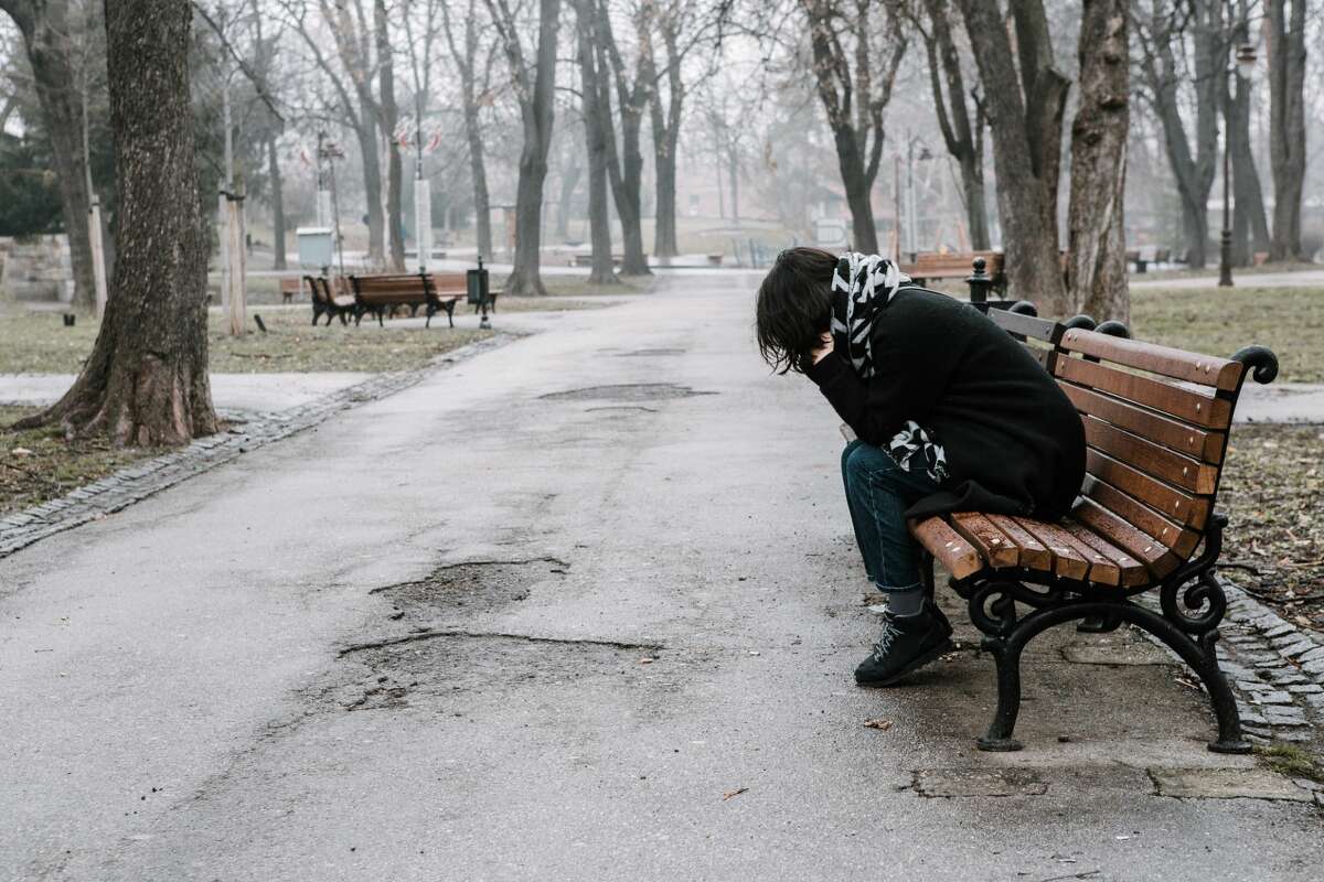 A file photo of a person sitting on a bench and having a tough time