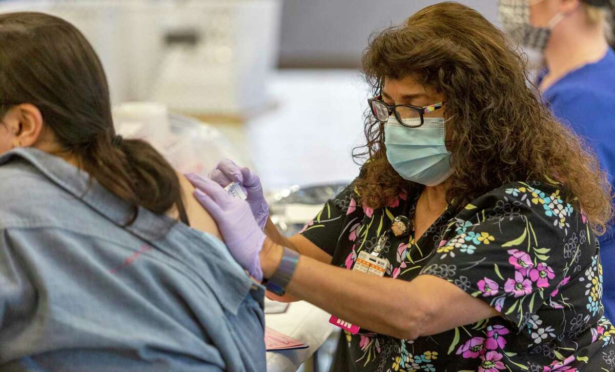 Registered nurse Estella Martinez, rights, gives a vaccination Wednesday, Nov. 17, 2021, to a person at a pop-up COVID 19 coronavirus vaccine clinic the Pearl.