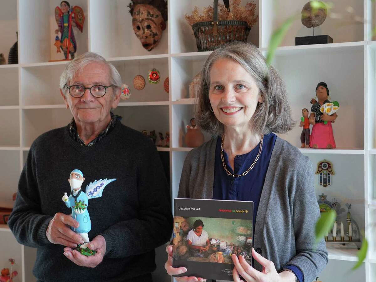 Alan Goldberg holds a COVID-19 themed sculpture of a winged doctor as he stands next to Gwen North Reiss, who wrote the text for the book: Oaxacan Folk Art: Response to Covid-19. Goldberg spearheaded a competition designed for Mexican folk artists to replace their lost livelihood.