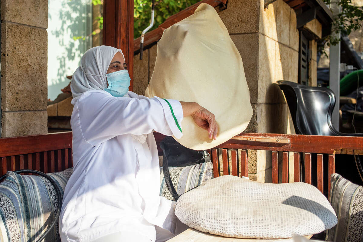 A local woman prepares traditional saj bread by stretching the dough very thin before placing it on a convex metal griddle at a seaside restaurant in Byblos, Lebanon on Monday, Nov. 22, 2021.