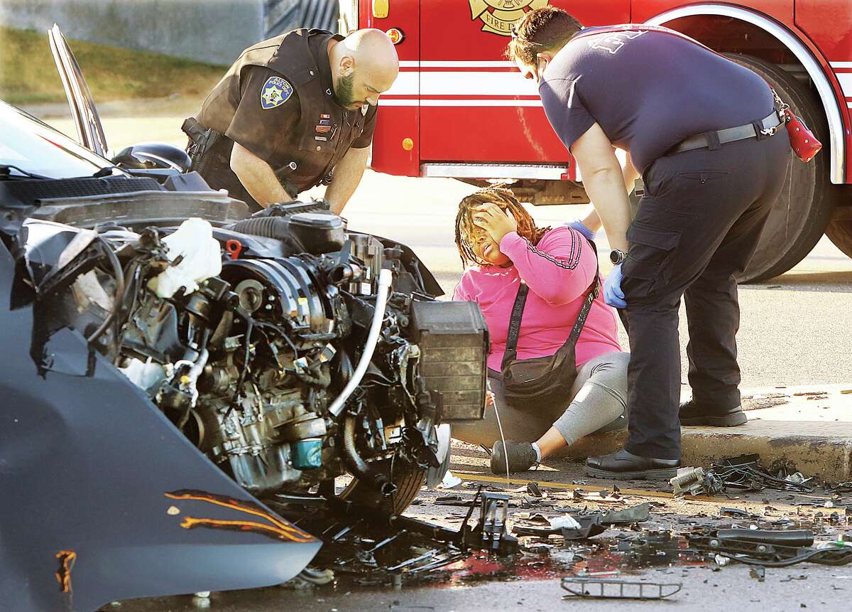 John Badman|The Telegraph The driver of a Kia Optima, sitting near her heavily damaged car, holds her head as emergency workers begin to treat her Thursday morning following a car crash between her vehicle and a Kia Sportage on Illinois 143 at the Cpl. Chris Belchik Memorial Expressway in Alton.