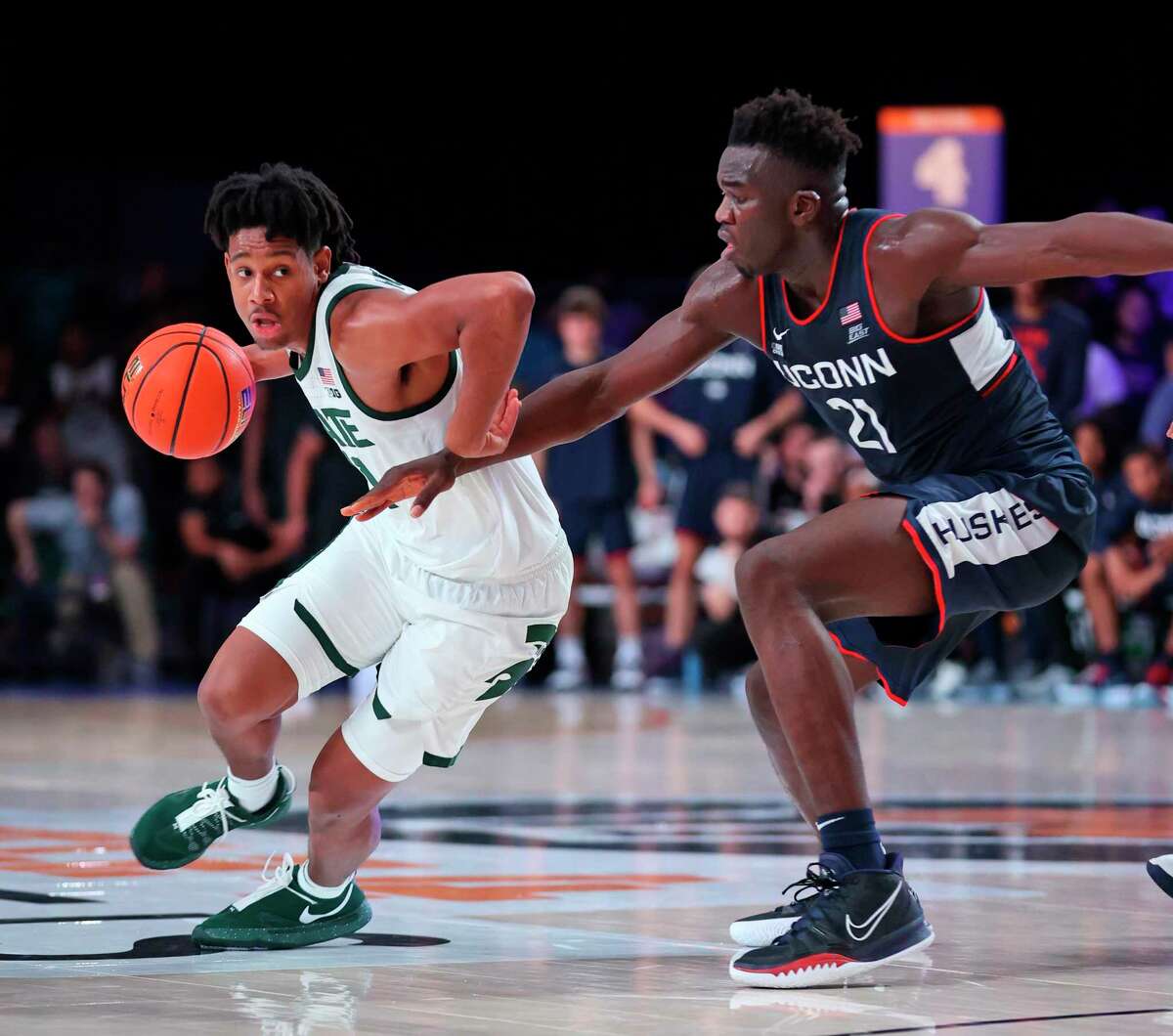 In this photo provided by Bahamas Visual Services, Michigan State guard A.J. Hoggard (11) drives as Connecticut forward Adama Sanogo (21) defends during an NCAA college basketball game at Paradise Island, Bahamas, Thursday, Nov. 25, 2021. (Tim Aylen/Bahamas Visual Services via AP)