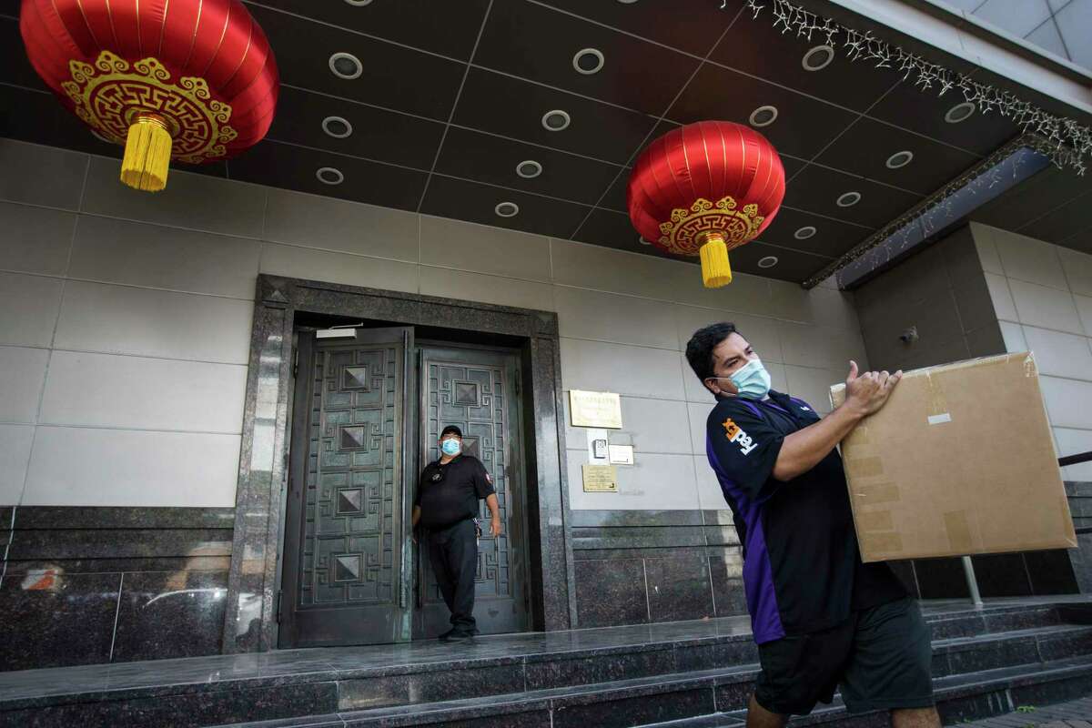 A delivery driver carries a box from the Consulate General of China in July as the office closed amid concerns about espionage. Reopening the office would be a small, positive step in U.S.-China relations.