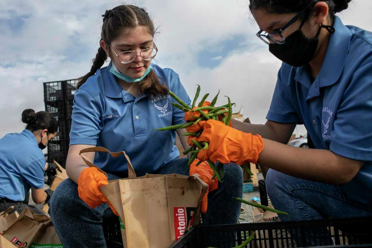 Alia Stacy, 18, and Araseli Castillo, 16, members of the Air Force Junior ROTC at John M. Harlan High School, help out at a San Antonio Food Bank distribution at Gustafson Stadium on Friday.