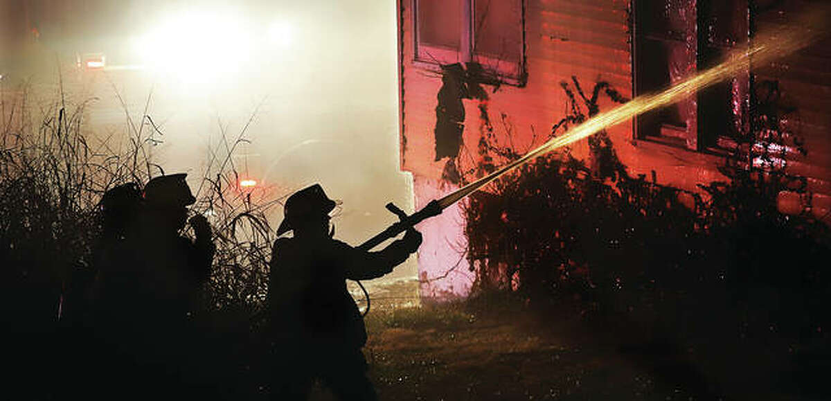 Firefighters direct a hose through a window in the rear of a burning house Friday night in the 2400 block of East Broadway. No injuries were reported.