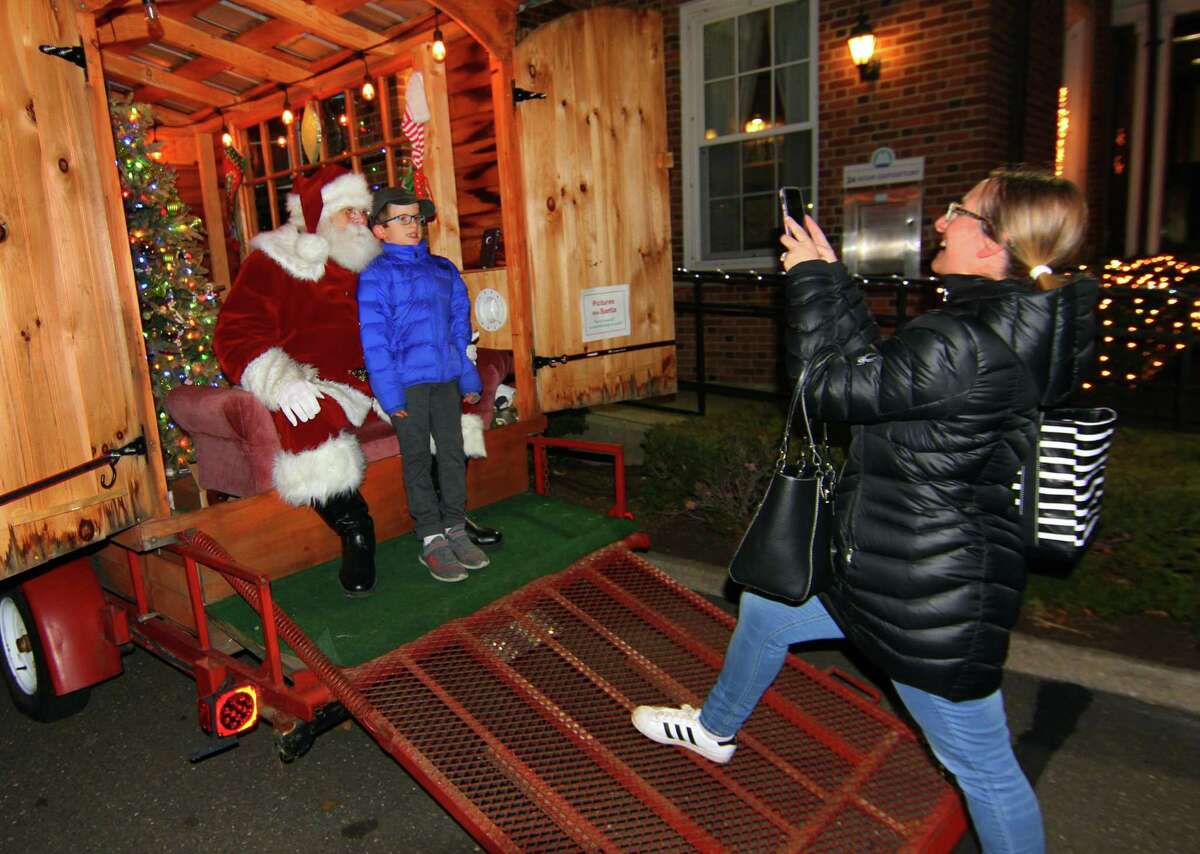 The Downtown Milford Business Association holds its Lamplight Stroll in Milford, Conn., on Friday December 3, 2021. Along with dozens of businesses open and vendors lining the green along Broad Street, various fun holiday stops along the way like a visit with Santa, horse-drawn carriage rides and carolers that move around from store to store.