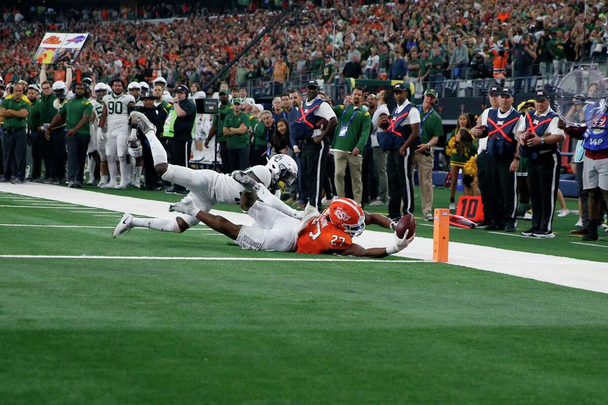 Oklahoma State running back Dezmon Jackson (27) dives and reaches the ball toward the end zone, but is stopped short by Baylor safety Jairon McVea (42) during the second half of the Big 12 Championship NCAA college football game in Arlington, Texas, Saturday, Dec. 4, 2021. (AP Photo/Roger Steinman)