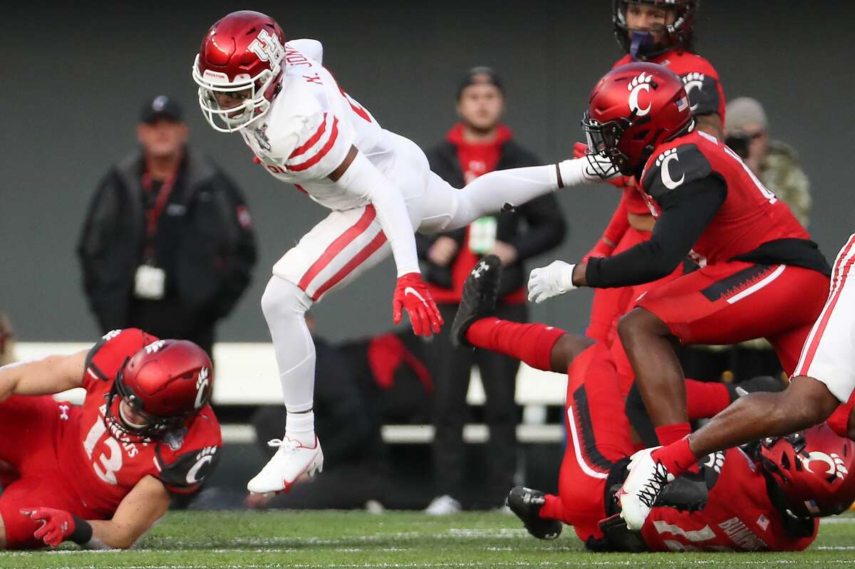 Houston cornerback Marcus Jones (8) leaps in the air as he is tripped up by Cincinnati cornerback Todd Bumphis (12) as he returns a kick during the first quarter of the AAC Championship game Saturday, Dec. 4, 2021 in Cincinnati.