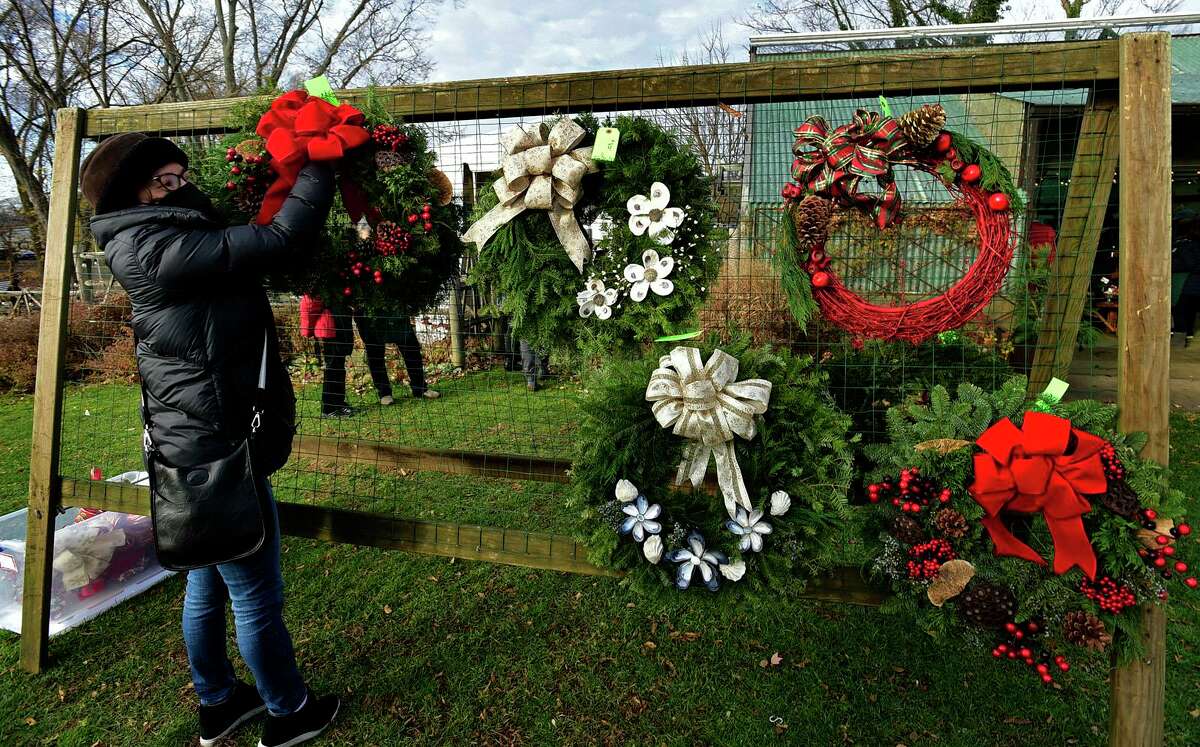 Cathy Chawla picks out a wreath at the Rowayton Gardeners annual Christmas Market selling holiday plants and decorations, including plum pudding, wreaths and ornaments Saturday, December 4, 2021, in Norwalk, Conn.
