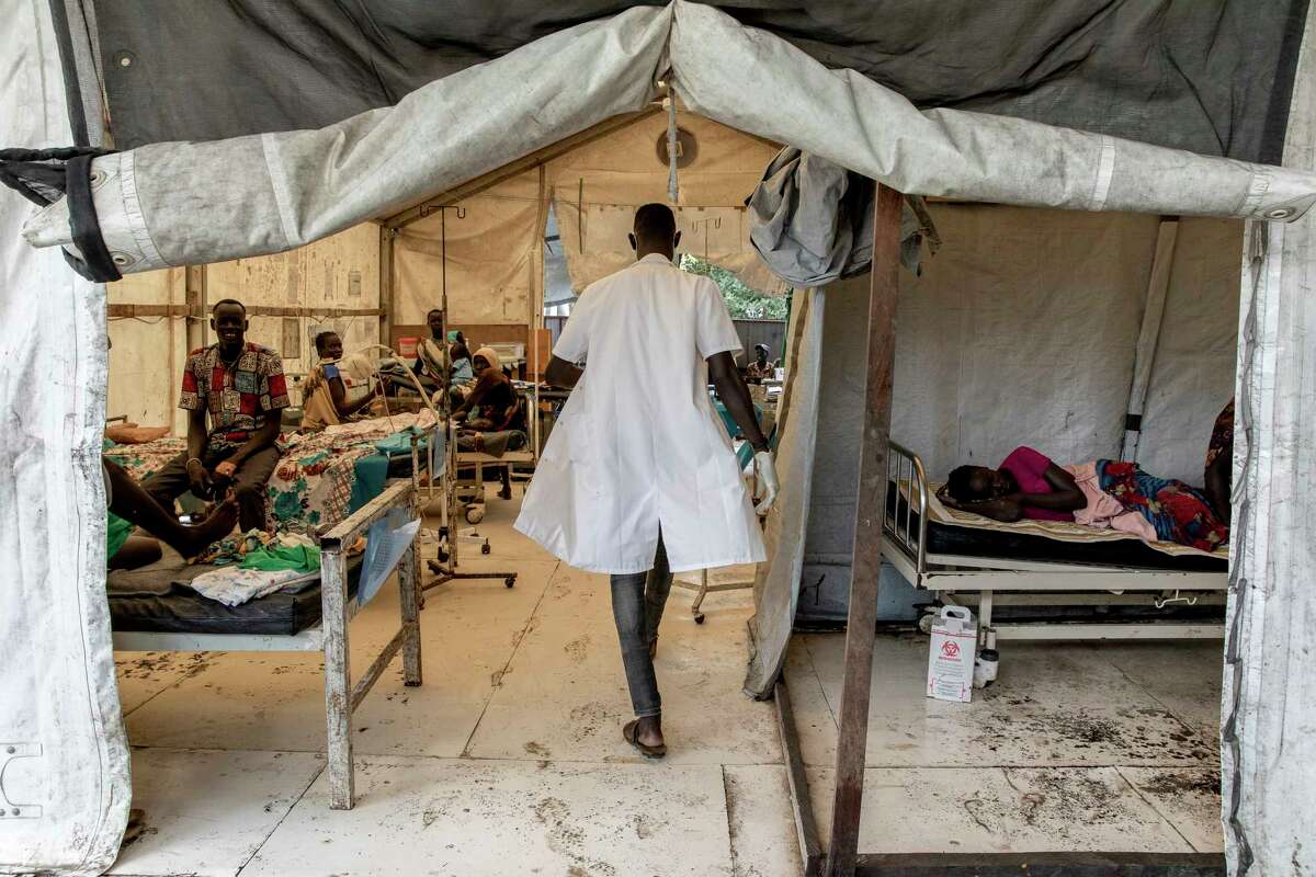 A Doctors Without Borders staffer walks into a hospital, past the bed of malaria patient Nyaka Yomlat, 16, in Old Fangak, South Sudan.
