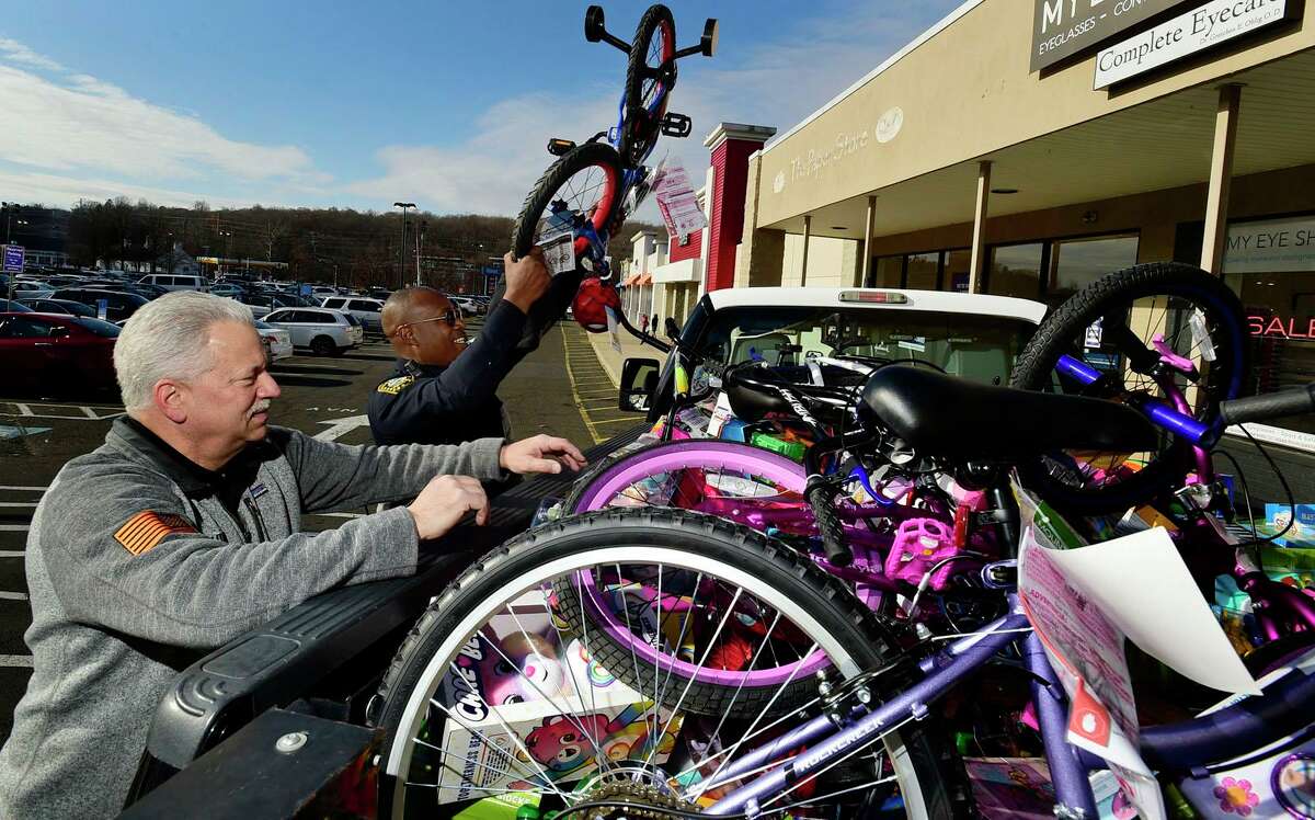 Officer Max Sixto, right, helps Bill Fitzmaurice of K&J Tree Service who donated 8 grocery carts full of toys and 6 bicycles during The Norwalk Police Department's annual Stuff-A-Cruiser gift fundraiser for underserved children Saturday, December 4, 2021, outside of Walmart on Main Avenue in Norwalk, Conn.