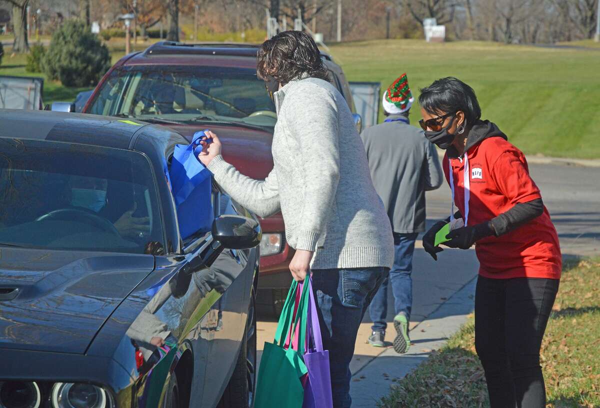 Vergia Burrell, right, website coordinator and advertisement director for the Metro East Professional Organization (MAPO), watches on Saturday as a volunteer delivers clothing items for Holiday Shoutout Drive-By Giveaway at Our Lady of the Snows Shrine.