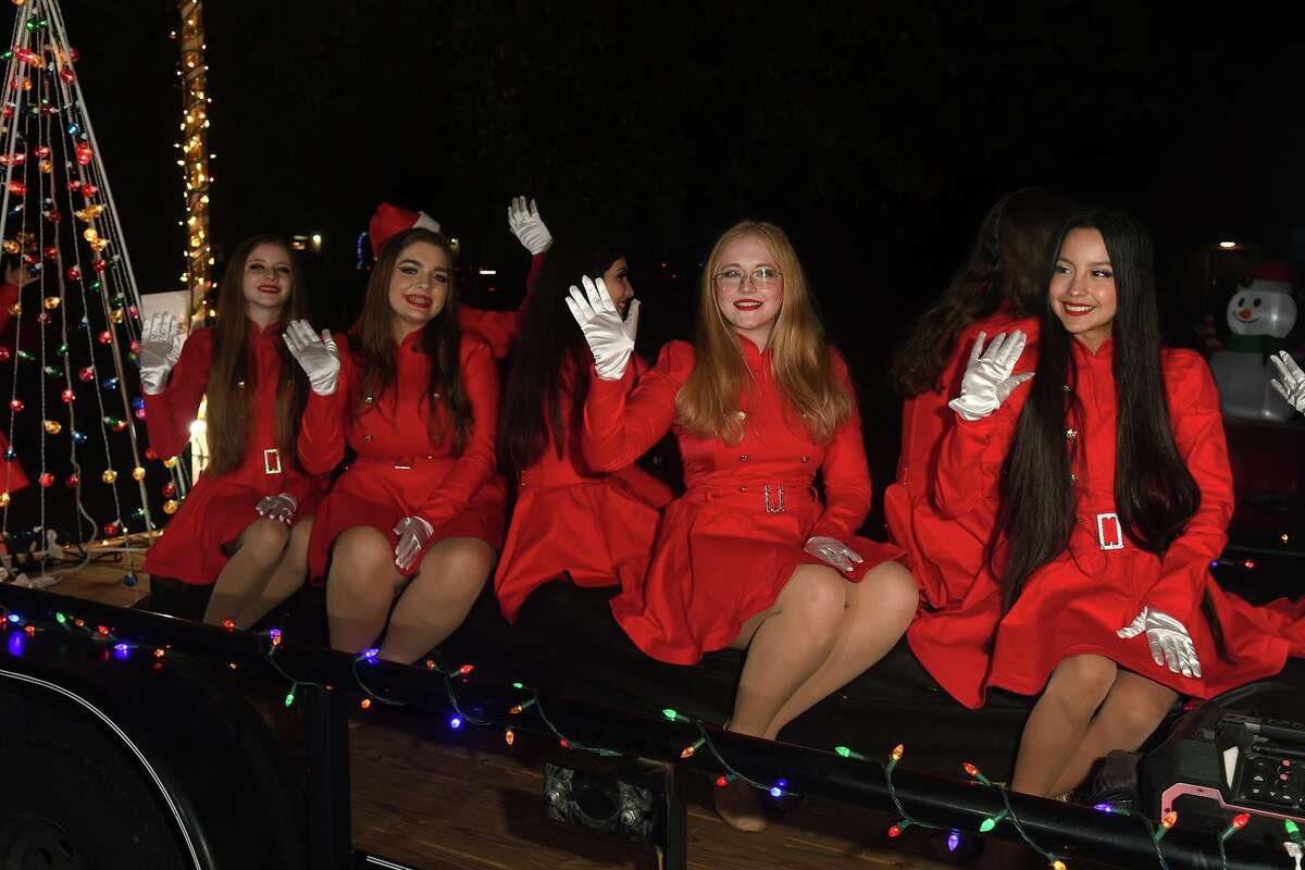 Magnolia West Fillies Dance Team members, including Nadia Ogden, from right, a sophomore, Caitlin Johnson, a senior, Kaylie Everett, a sophomore, and Lily Snyder, a sophomore, wave to the crowd during the Annual Magnolia Christmas Parade of Lights in downtown Magnolia on Saturday.